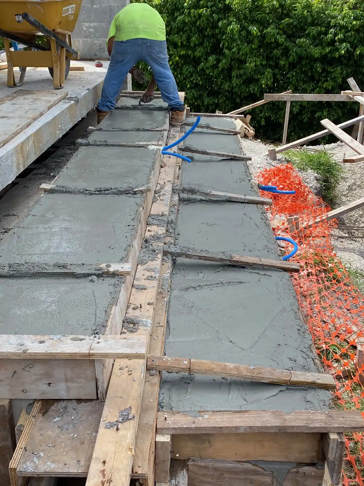 A crew finishes a freshly poured floating concrete step inside timber formwork on a South Florida job site.